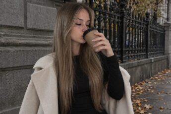 Осенняя фотосессия с кофе: пальто, кованая ограда и стакан в руке