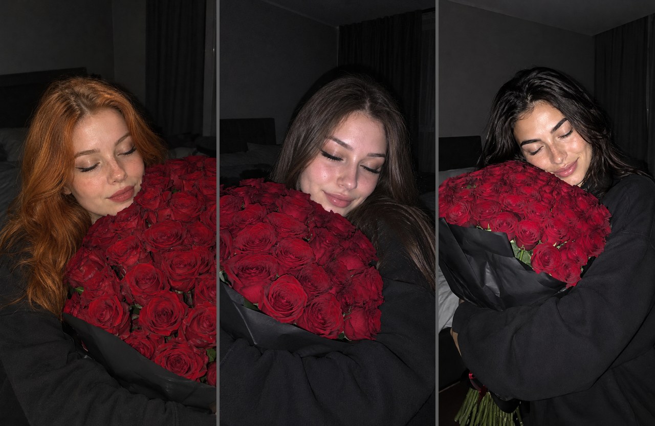 Фото с большим букетом роз: три девушки в тёмной спальне обнимают красные розы, глаза закрыты