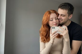 Фото пары в зеркале: рыжая девушка с белым айфоном, парень в чёрной футболке прижался к ней щекой